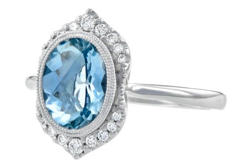 Dive into this calming blue oval shaped Aquamarine weighing 1.56 carat. The center gem is bezel set in 14k white gold with milgrain beaded edging for a hint of vintage styling. It's framed in brilliant white diamonds that come to a point at the top and bottom of gem. The diamonds total .14ct and are a bright white G color grade and SI1/SI2 clarity grade.ming blue oval shaped Aquamarine weighing 1.56 carat. The center gem is bezel set in 14k white gold with milgrain beaded edging for a hint of vintage styling. It's framed in brilliant white diamonds that come to a point at the top and bottom of gem. The diamonds total .14ct and are a bright white G color grade and SI1/SI2 clarity grade.